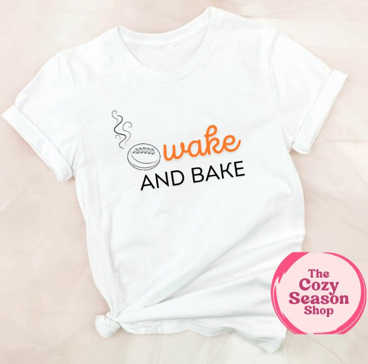 A white t-shirt with the text 'WAKE AND BAKE' and a graphic of a loaf of sourdough printed on it