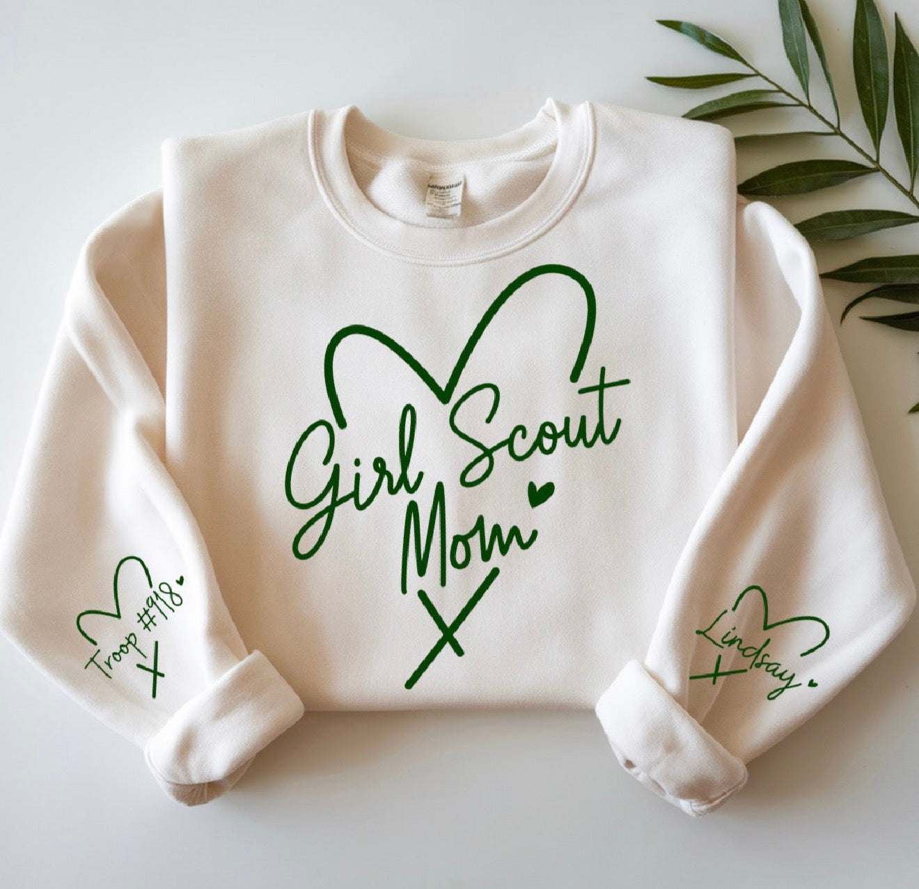 White sweatshirt with 'Girl Scout Mom' text and green hearts on a light background