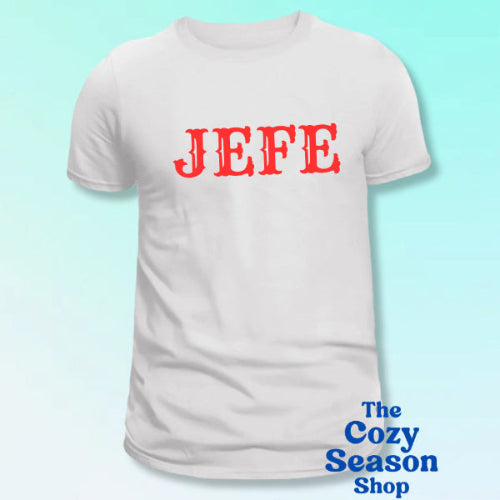 White t-shirt with red 'JEFE' text on a light blue background, branded with 'The Cozy Season Shop'.
