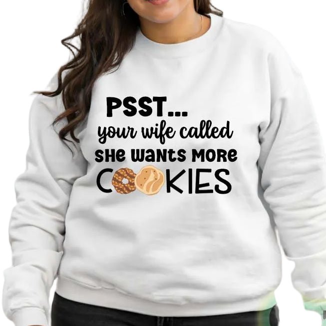 A woman wearing a white unisex pullover sweatshirt with the text 'PSST... your wife called she wants more COOKIES' on it.