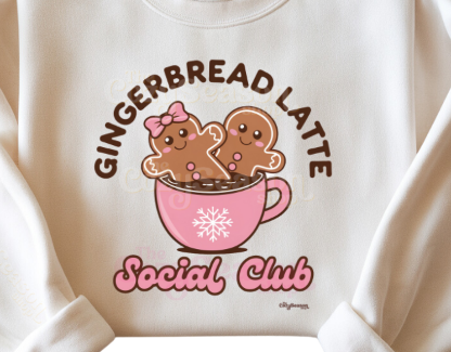 A white crewneck sweatshirt with 'Gingerbread Latte' text and a graphic of two gingerbread figures in a pink cup, surrounded by a pink and brown color scheme. The sweatshirt has a 1x1 ribbed collar, cuffs, and a waistband.