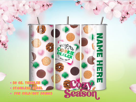 A 20oz stainless steel travel tumbler with a white base color, featuring printed images of various girl scout cookies and decorative elements, such as polka dots and text. A clear lid and a reusable straw are included.