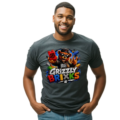 A man wearing a dark gray graphic t-shirt with a colorful 'Grizzly Brixks' bear design, paired with blue jeans, standing against a light gray studio background.