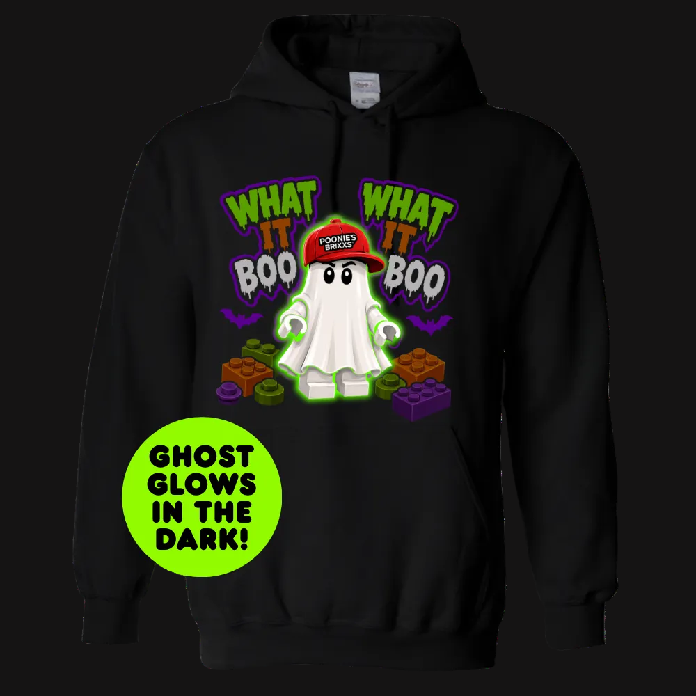 A black pullover hoodie featuring a cartoon ghost graphic with the text 'WHAT IT BOO' and 'WHAT IT BOO' in green and purple, plus a bright green circular badge that reads 'GHOST GLOWS IN THE DARK!'. The hoodie is shown on a plain white background.