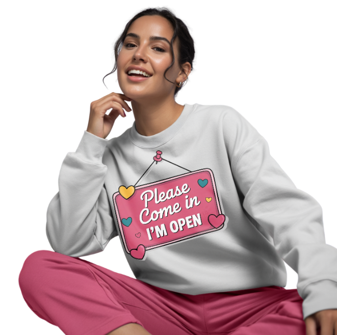 Person wearing a white sweatshirt with a colorful sign that reads: "PLEASE COME IN, I'M OPEN" design and pink pants on a white background