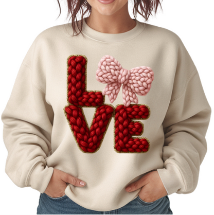 Woman wearing a cream sweater with red and pink 'LOVE' design on a white background