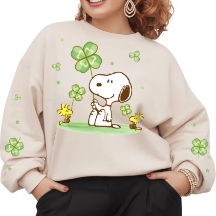 Woman wearing a beige sweatshirt with cartoon characters and shamrocks on a white background