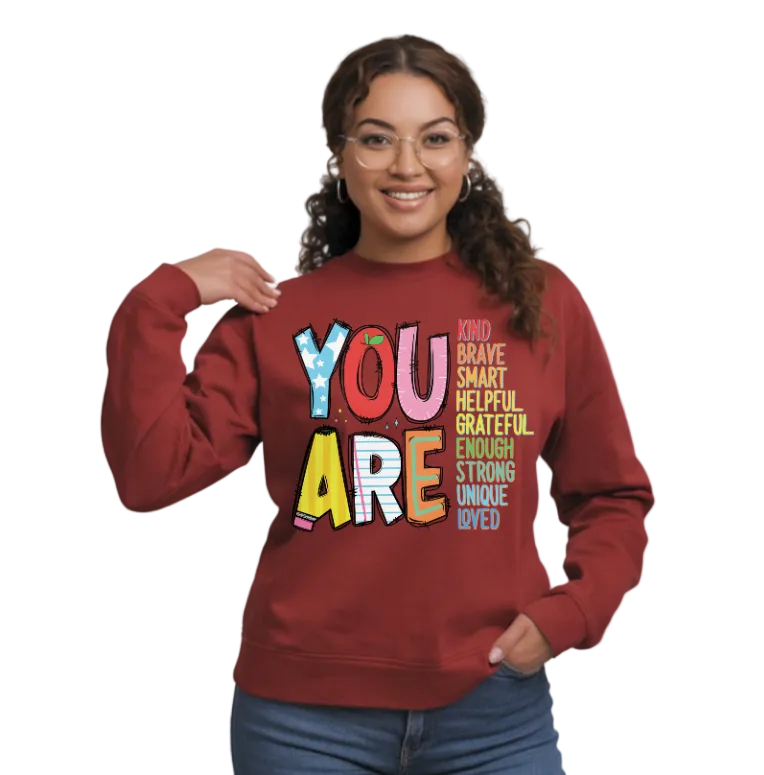Person wearing a red sweatshirt with motivational text on a plain background