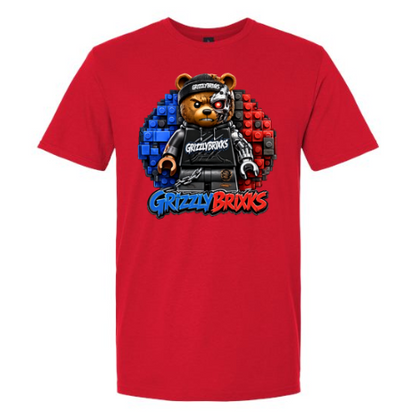 A red short-sleeve crewneck t-shirt featuring a 'Grizzly Brixks' graphic on the chest. The graphic depicts a bear character wearing a black outfit and cap, set against a circular background of blue and red building blocks, with 'Grizzly Brixks' written in stylized blue and red text below.
