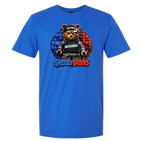 A royal blue short-sleeve t-shirt featuring a central graphic of a teddy bear wearing a black outfit and cap, set against a circular background split into blue and red brick patterns, with the text 'Grizzly Brixks' below.