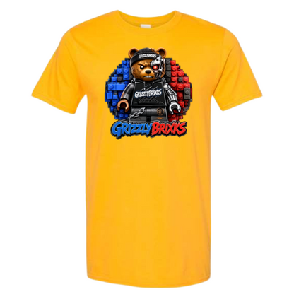 A bright yellow short-sleeve crewneck t-shirt featuring a central graphic of a grizzly bear wearing a black cap and black hoodie, with blue and red brick patterns behind it and the text 'Grizzly Bricks' below.
