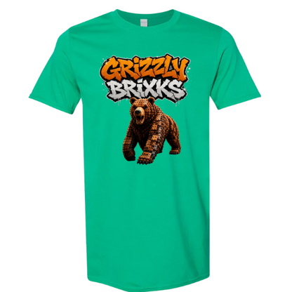 A green short-sleeve crewneck t-shirt featuring a graphic print of a brown bear and the text 'Grizzly Brixxs' in orange and white graffiti-style lettering, displayed on a solid white background.