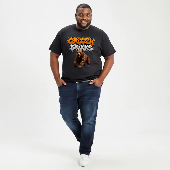 A man modeling a black short-sleeve graphic t-shirt with 'Grizzin Brooks' in orange and white text and a grizzly bear print, paired with dark blue jeans and white sneakers, against a plain white studio background.