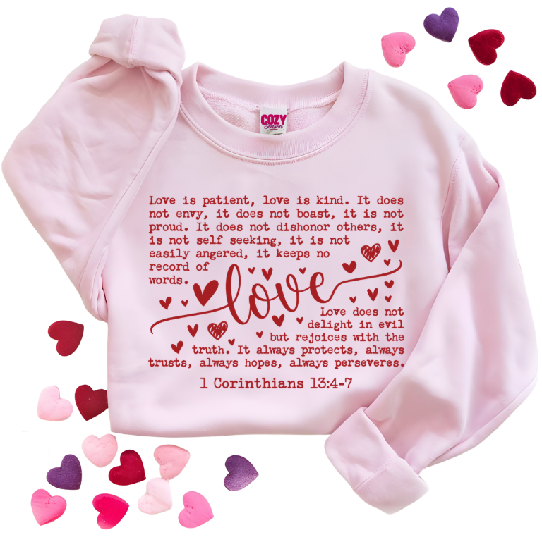 Pink sweatshirt with corinthians 13:4-7 scripture in red text and hearts, surrounded by colorful hearts on a white background