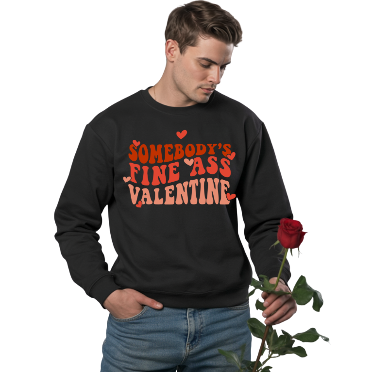 Man wearing a black sweatshirt with red text holding a rose on a white background. the sweatshirt has text: SOMEBODY'S FINE ASS VALENTINE" in various red shades.