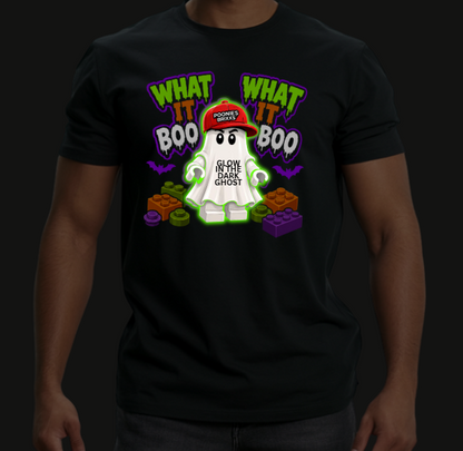 A man wearing a black t-shirt with a colorful graphic of a glowing white ghost wearing a red cap that says 'GLOW IN THE DARK GHOST'. The graphic also features the text 'WHAT IT BOO' in green and white.